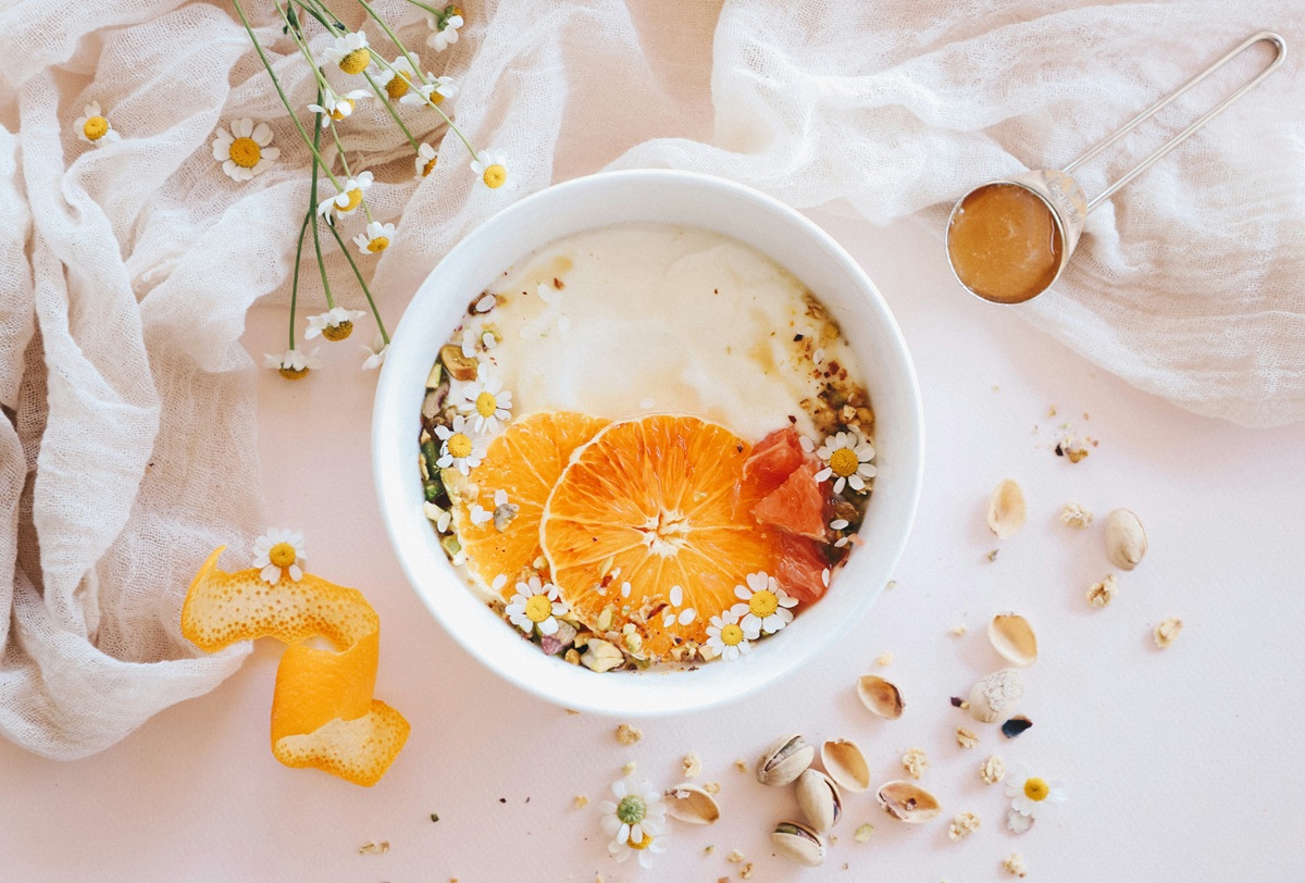 オレンジとカモミールの花で飾られたオートミール（またはヨーグルトボウル）。健康的でおしゃれな朝食のイメージ。