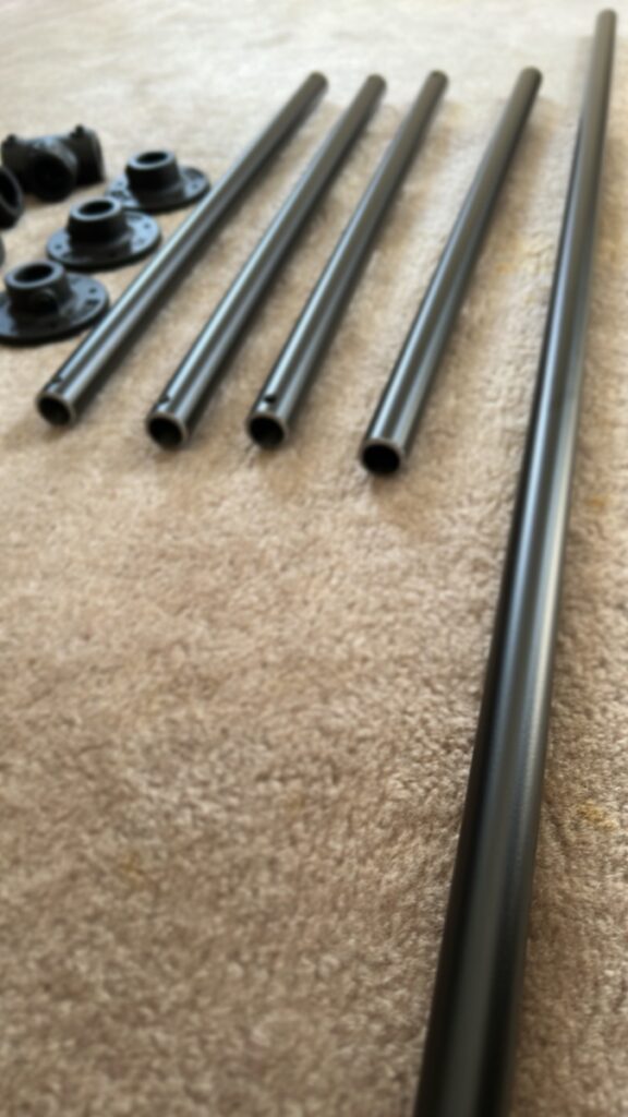カーペットの上に並べられた、黒いDIY用のアイアンパイプと継手パーツ。