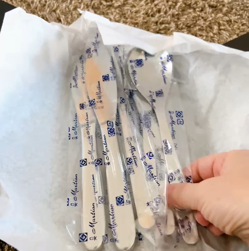 柳宗理カトラリーの個包装を手で持っている様子。白い薄紙の袋には、青色で「Martian」のロゴがパターン状に印刷されている。