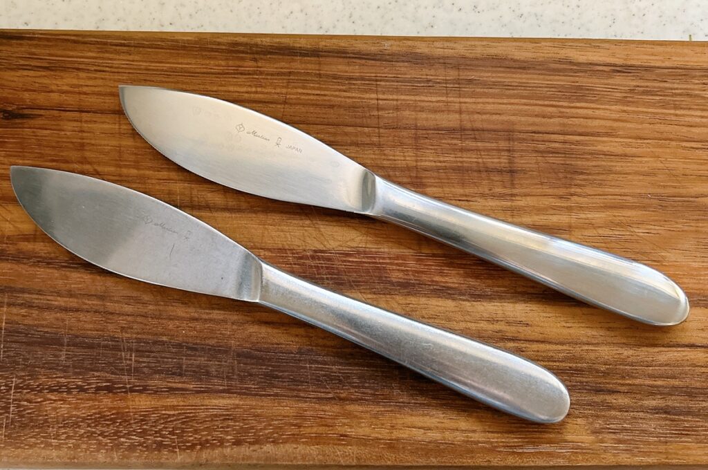 柳宗理のディナーナイフ2本を比較。上が新品(ふるさと納税返礼品)、下が20年愛用したもの。つや消しステンレスの質感の変化が見て取れる。