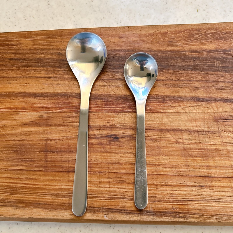 柳宗理のステンレス製スプーン2本の比較。左が新しく迎えたティースプーン(返礼品)、右がひと回り小さいコーヒースプーン。木製のボードに乗せられた写真。