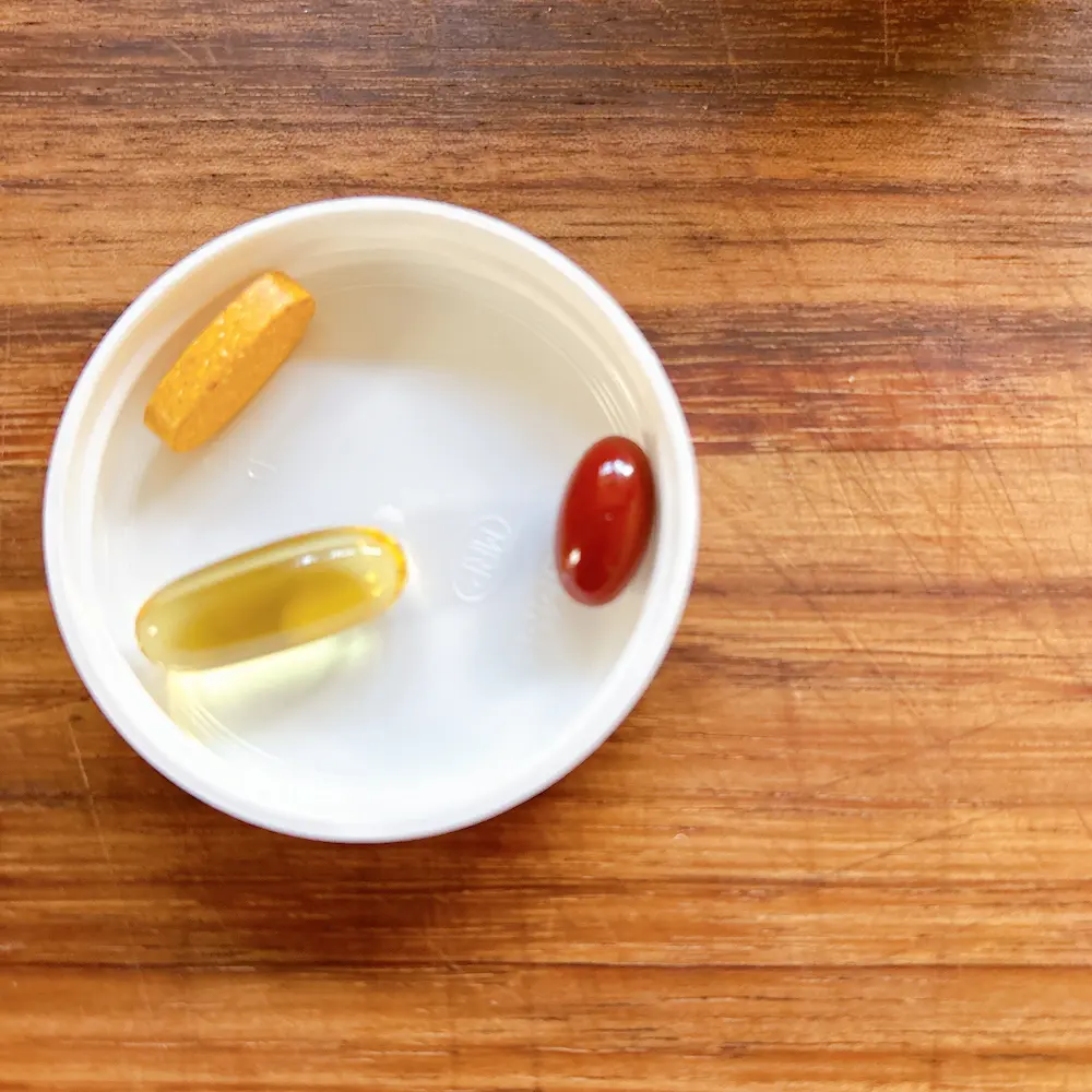 毎朝まとめて飲んでいるiHerbのサプリ3粒（ツーパーデイ、コエンザイムQ10、オメガ3）を白いフタに乗せた比較写真