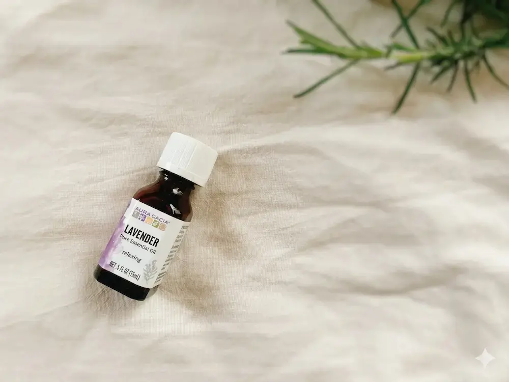 iHerbで購入したオーラカシア（Aura Cacia）のラベンダー精油。リネン素材の背景にローズマリーの枝を添えたナチュラルな雰囲気。